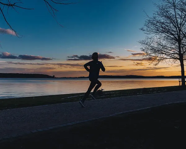 a woman  running on a path next to a body of water